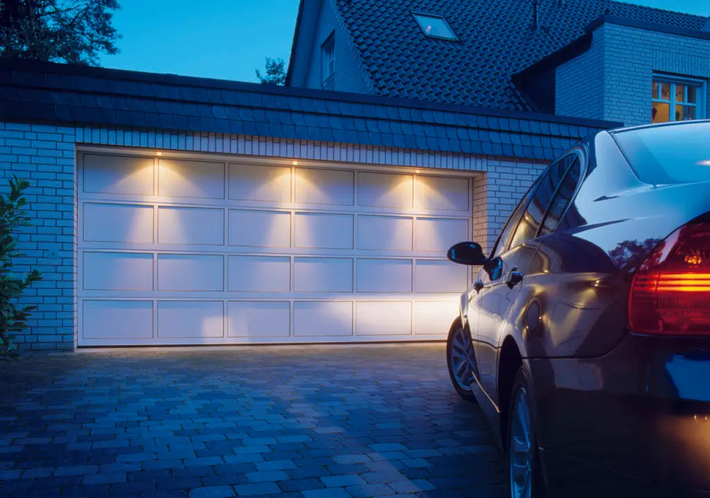 Sektionaltor an einer modernen Garage bei Abendbeleuchtung